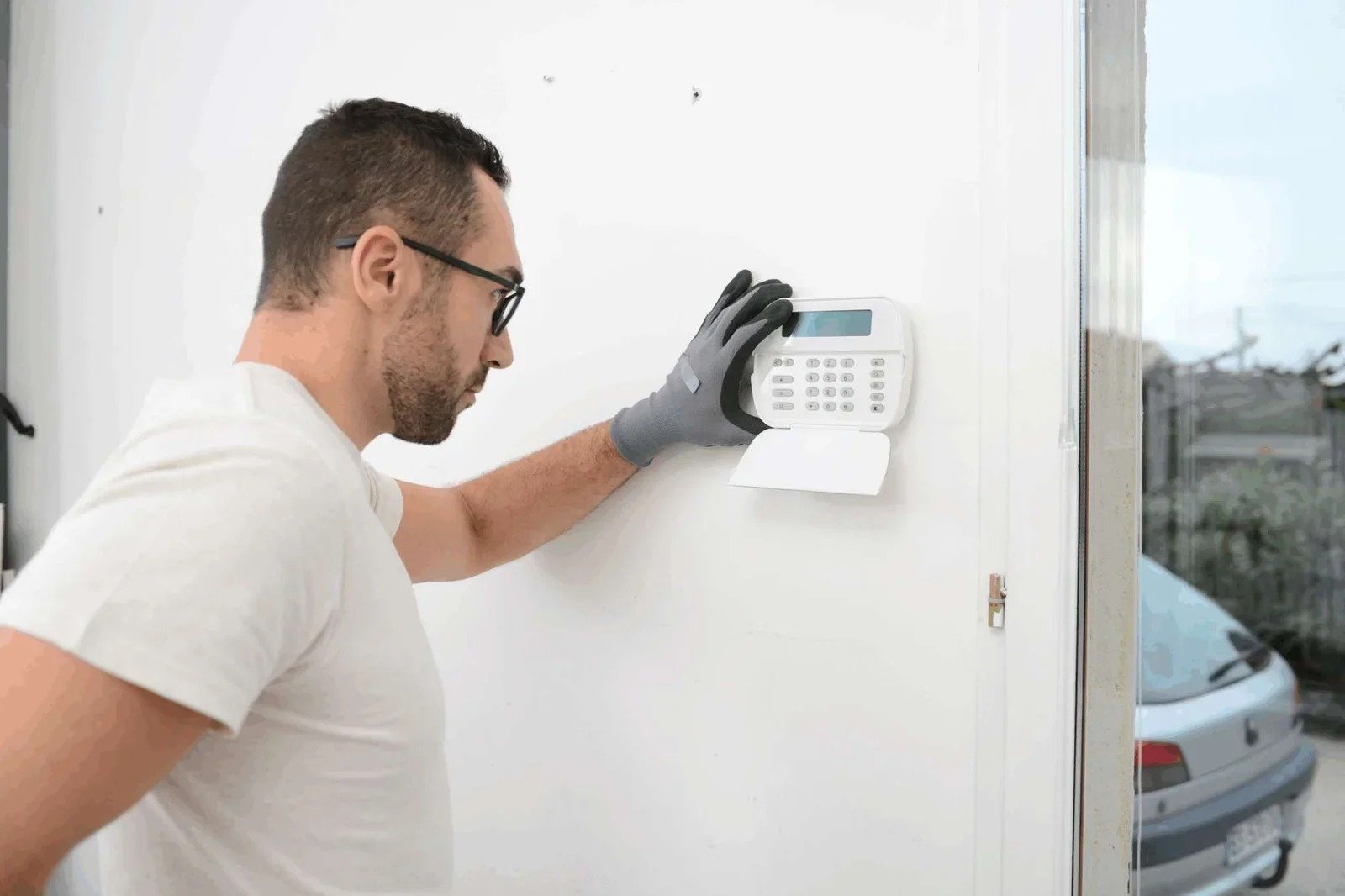 An expert technician installs a security alarm keypad on a wa...