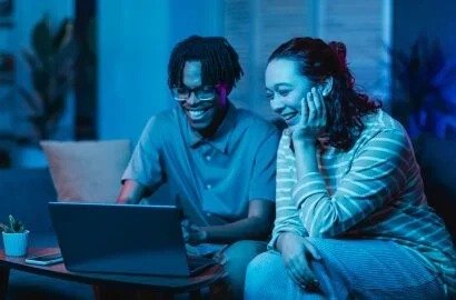 A couple monitors their home security system on a laptop, rep...